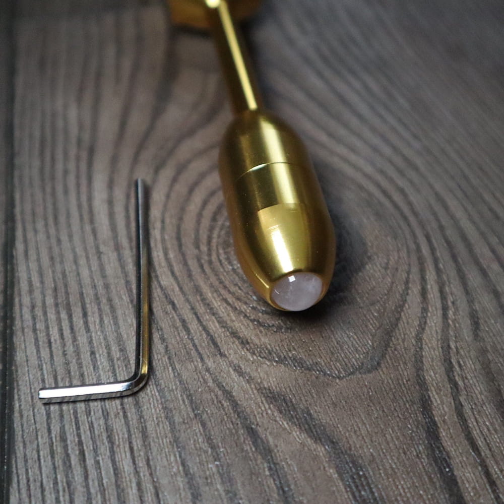 Brass-colored bullet-shaped tuning fork with white tip for biofield healing therapy