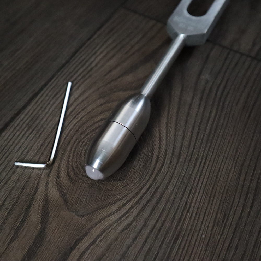 Metal screwdriver with silver handle and shaft beside 68.05 Hz Weighted Tuning Fork