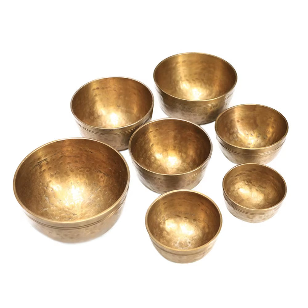 Seven brass Tibetan singing bowls grouped together in a meditation set