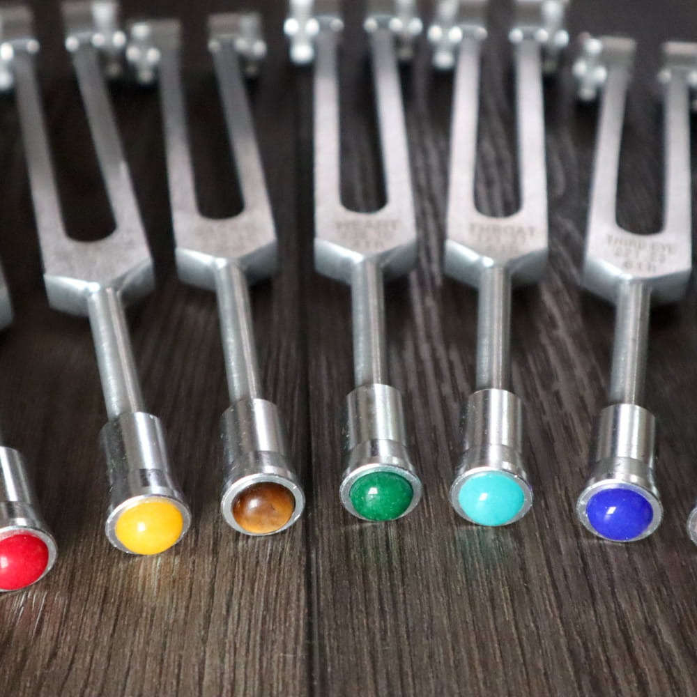 Colorful Chakra Tuning Fork Gemstone Attenuator 7pc Set arranged in a row