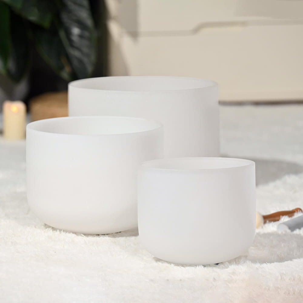 Three white crystal singing bowls in a row from Frosted Quartz Crystal Singing Bowl Set