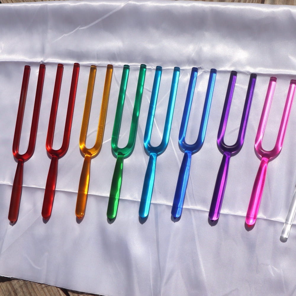 Row of colorful metallic tuning forks in rainbow order for sound healing therapy