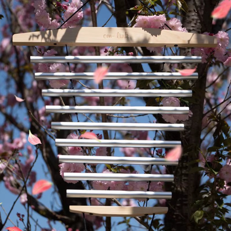 White slatted wooden wind chime among cherry blossoms in 9 Notes Swinging Wind Chime