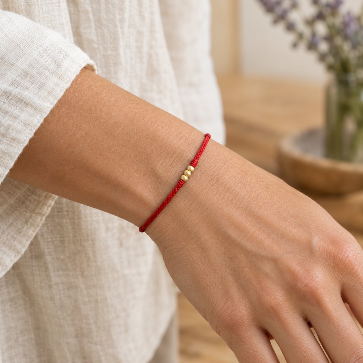999 Gold Mini Red String Bracelet with Three Beads for Luck, worn on the wrist by a woman