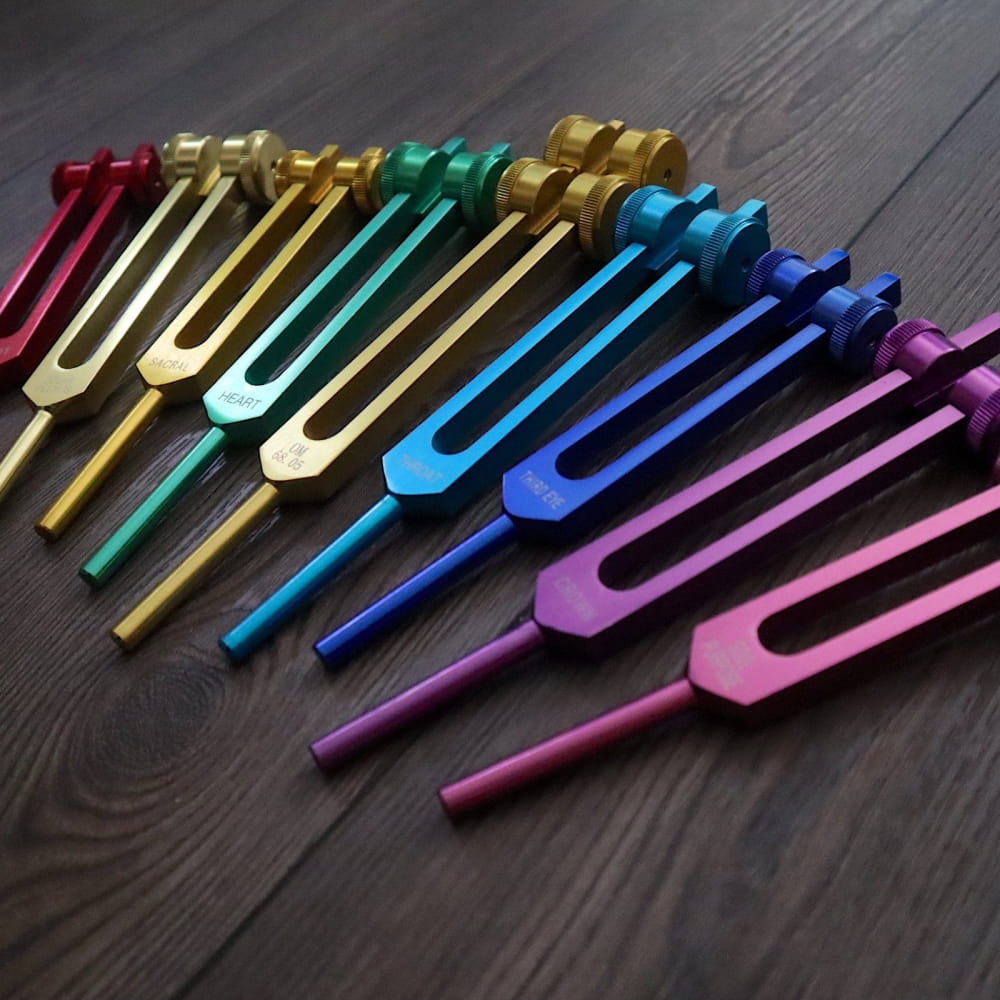 Colorful metallic tuning forks arranged in rainbow pattern from 9pc Chakra Tuning Fork Set