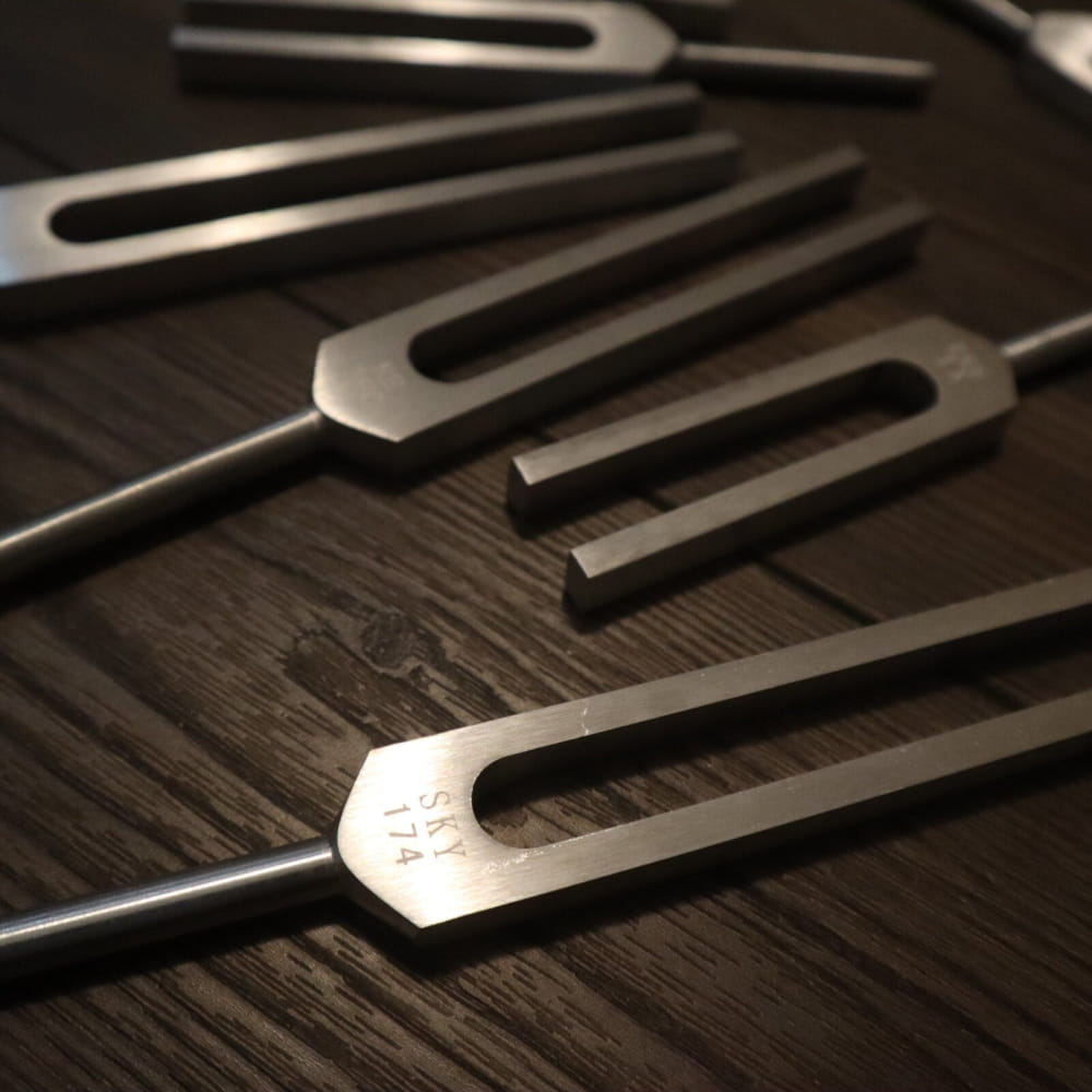 Several tuning forks on a wooden surface from the 9pc Solfeggio Frequencies Set