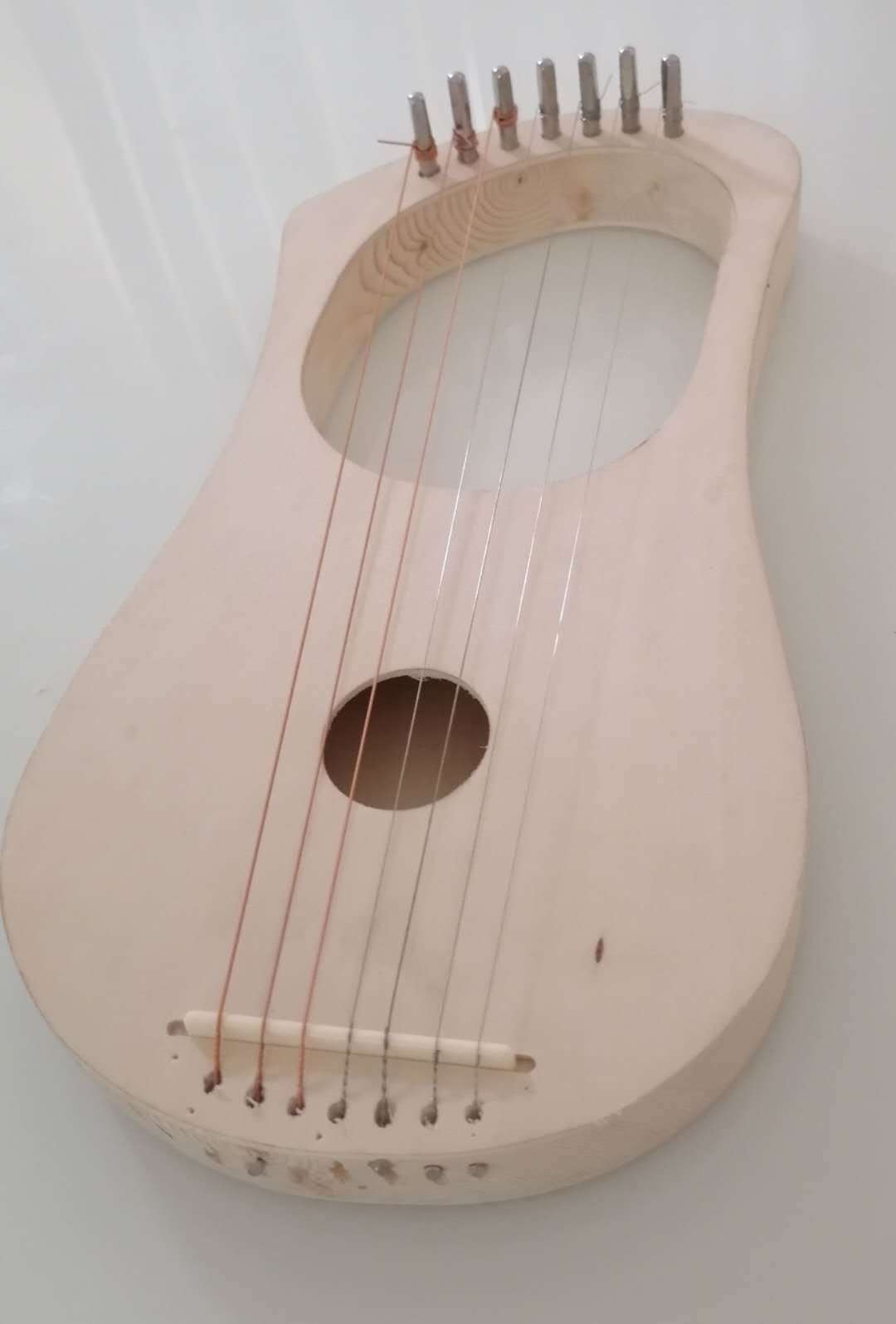 Unfinished wooden lyre harp with strings and tuning pegs in Beginner Lyre Harp Kit