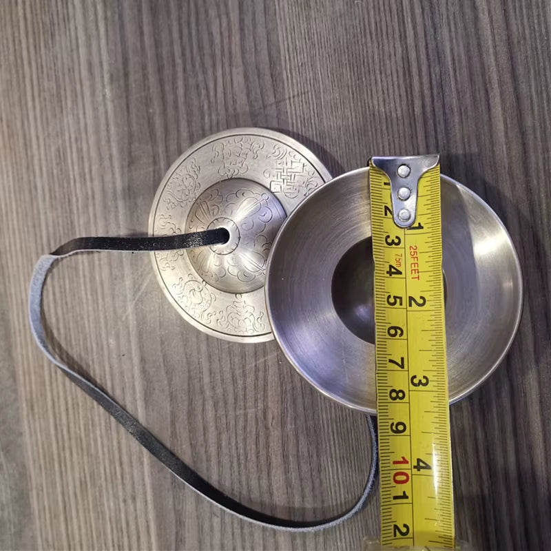 Brass Buddha Hand Cymbals connected by a black cord for meditation practice