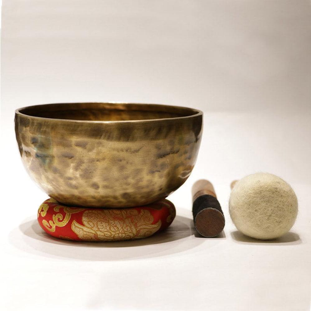 Hammered metal Tibetan Singing Bowl on a decorative red cushion for meditation