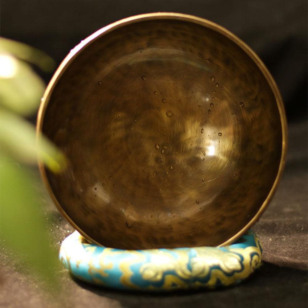 Bronze singing bowl on turquoise and gold cushion for meditation and relaxation