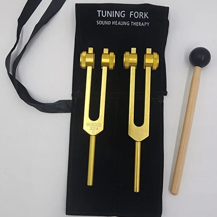 Two golden tuning forks and a mallet on a black display for Cellulite Tuning Fork Set