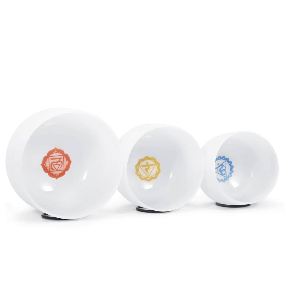 Three white ceramic bowls with colored chakra symbols in Chakra Symbol Crystal Singing Bowl Set