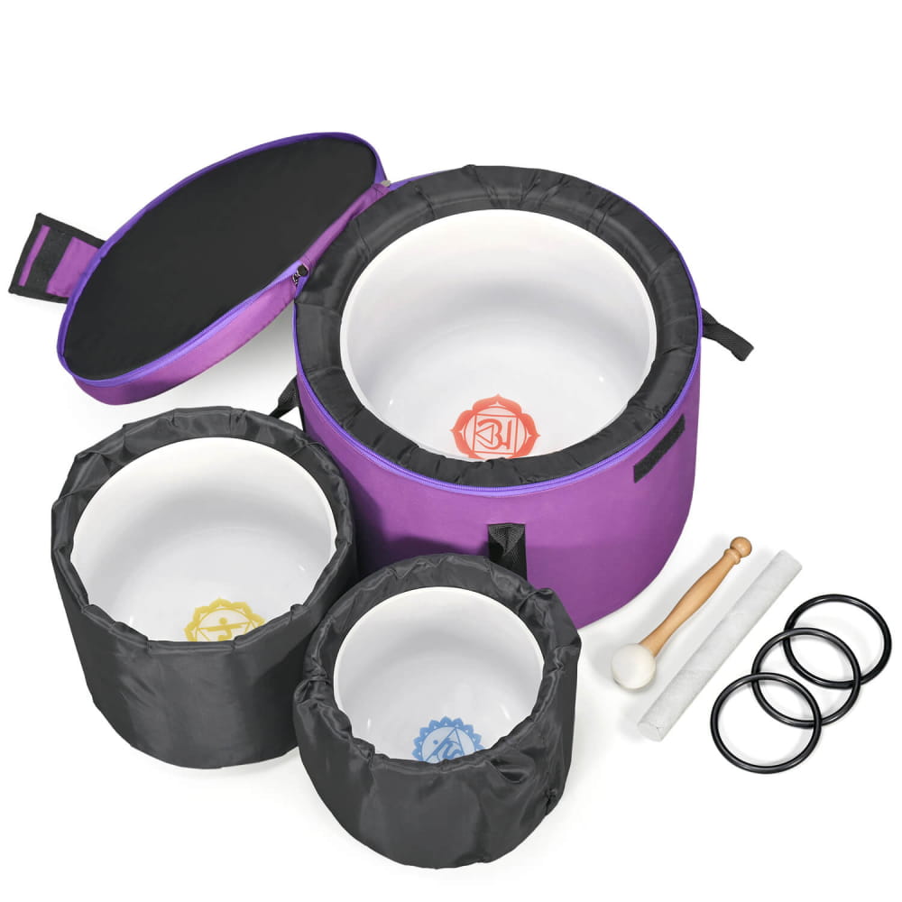 Set of three Chakra Symbol Crystal Singing Bowls in purple and black cases with accessories