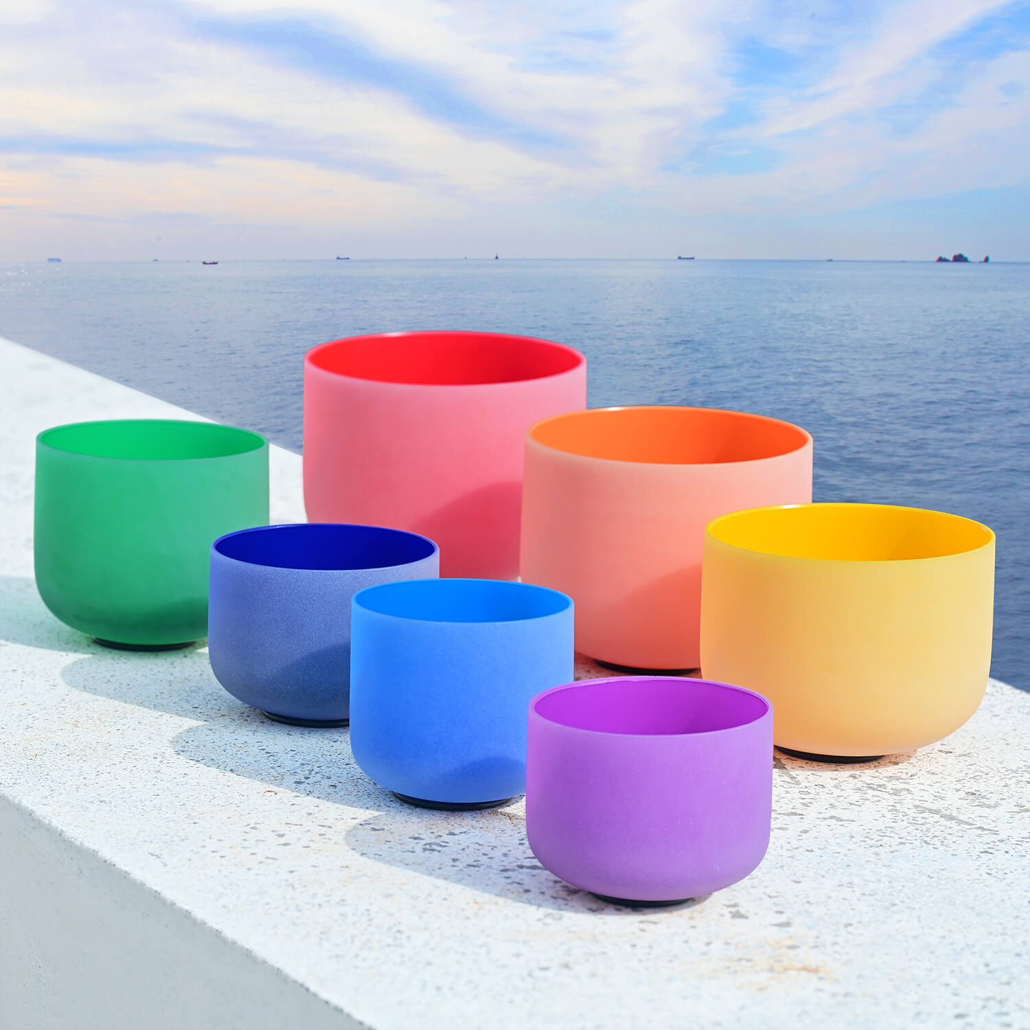 Seven colorful crystal singing bowls in rainbow arrangement for chakra healing