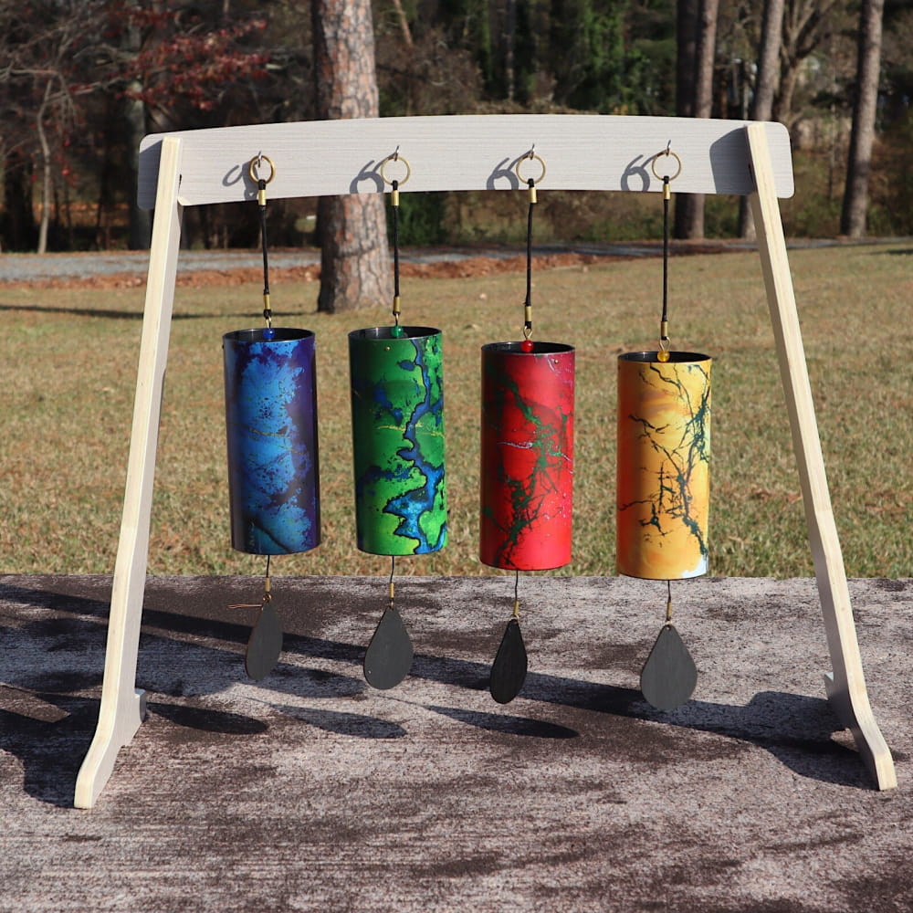 Four colorful cylindrical Koshi chimes on a wooden stand representing elemental energies