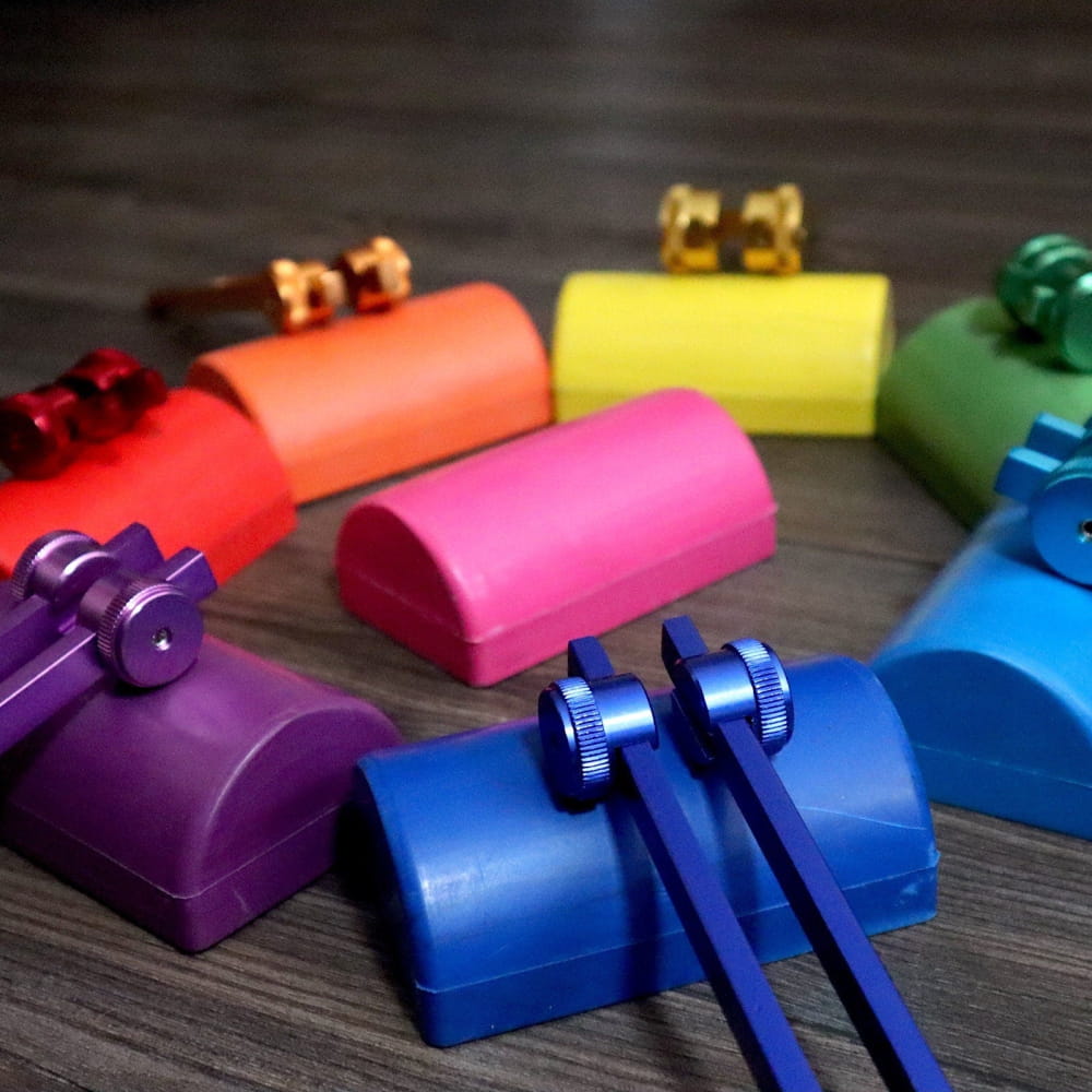 Colorful plastic boomwhackers in rainbow pattern with mallets near Chakra Tote Bags