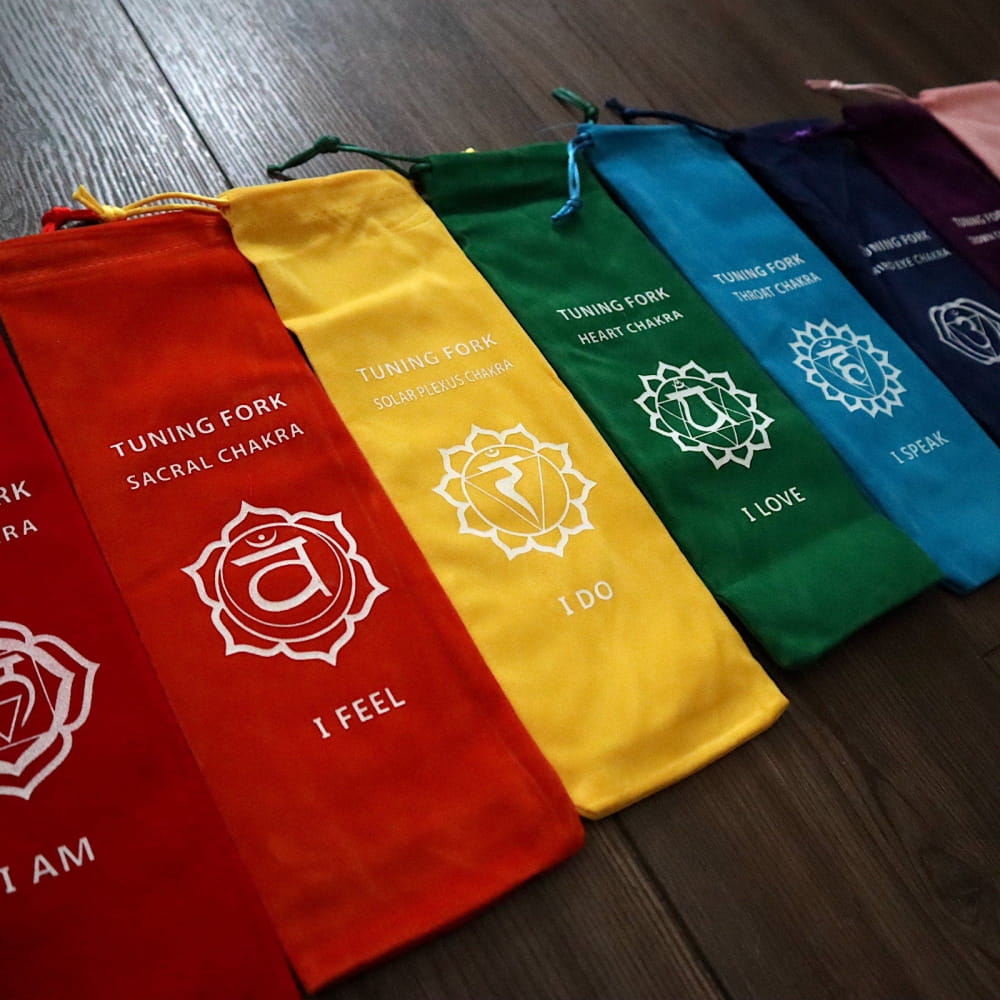 Rainbow-colored fabric pouches with chakra symbols and affirmations on Colorful Chakra Canvas Tote Bags