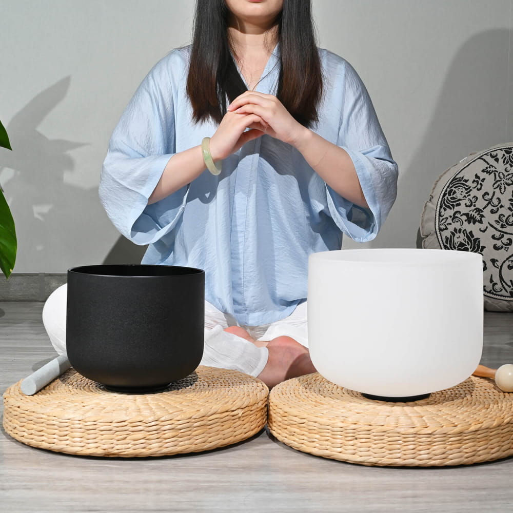 Two crystal singing bowls in black and white on woven straw mats for sound healing