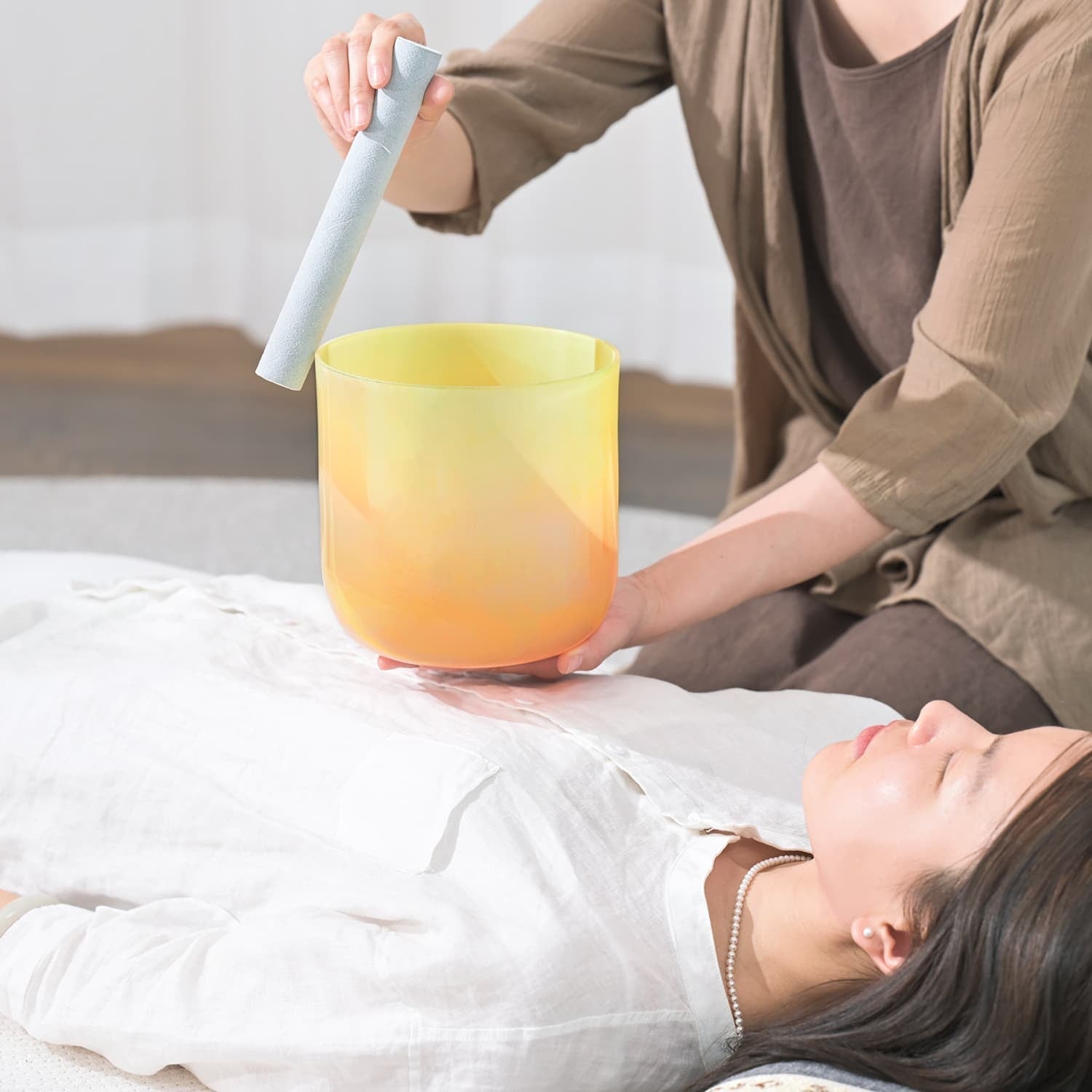 Yellow and orange Crystal Singing Bowl used in sound therapy session for healing