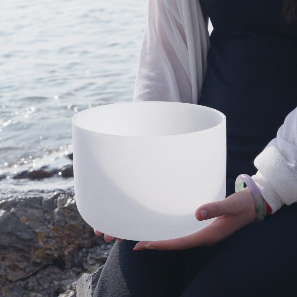 White crystal singing bowl held in hands for Throat Chakra meditation and healing