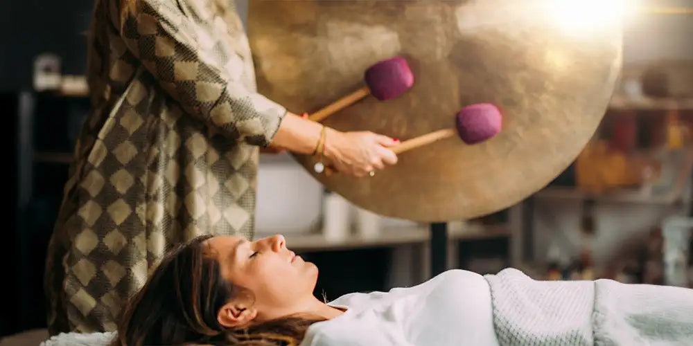 A large, golden-toned gong with two purple mallets resting on its surface.