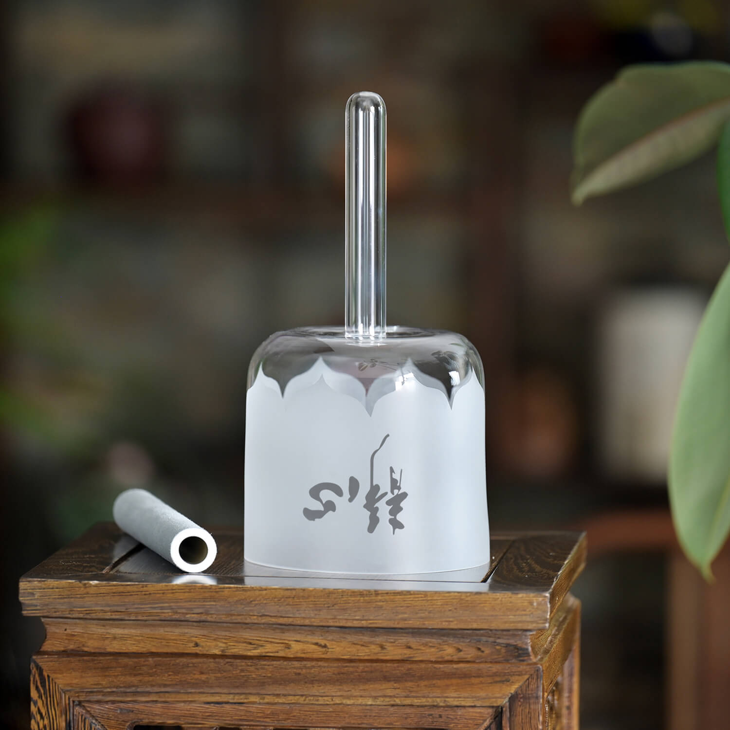 Frosted glass water pipe with a straight tube stem next to Handle Heart Crystal Singing Bowl