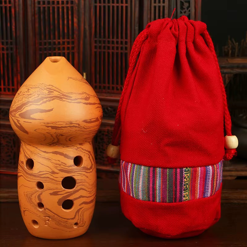 Clay Ocarina flute with holes next to a red drawstring pouch, Handmade Ceramic Xun Flute