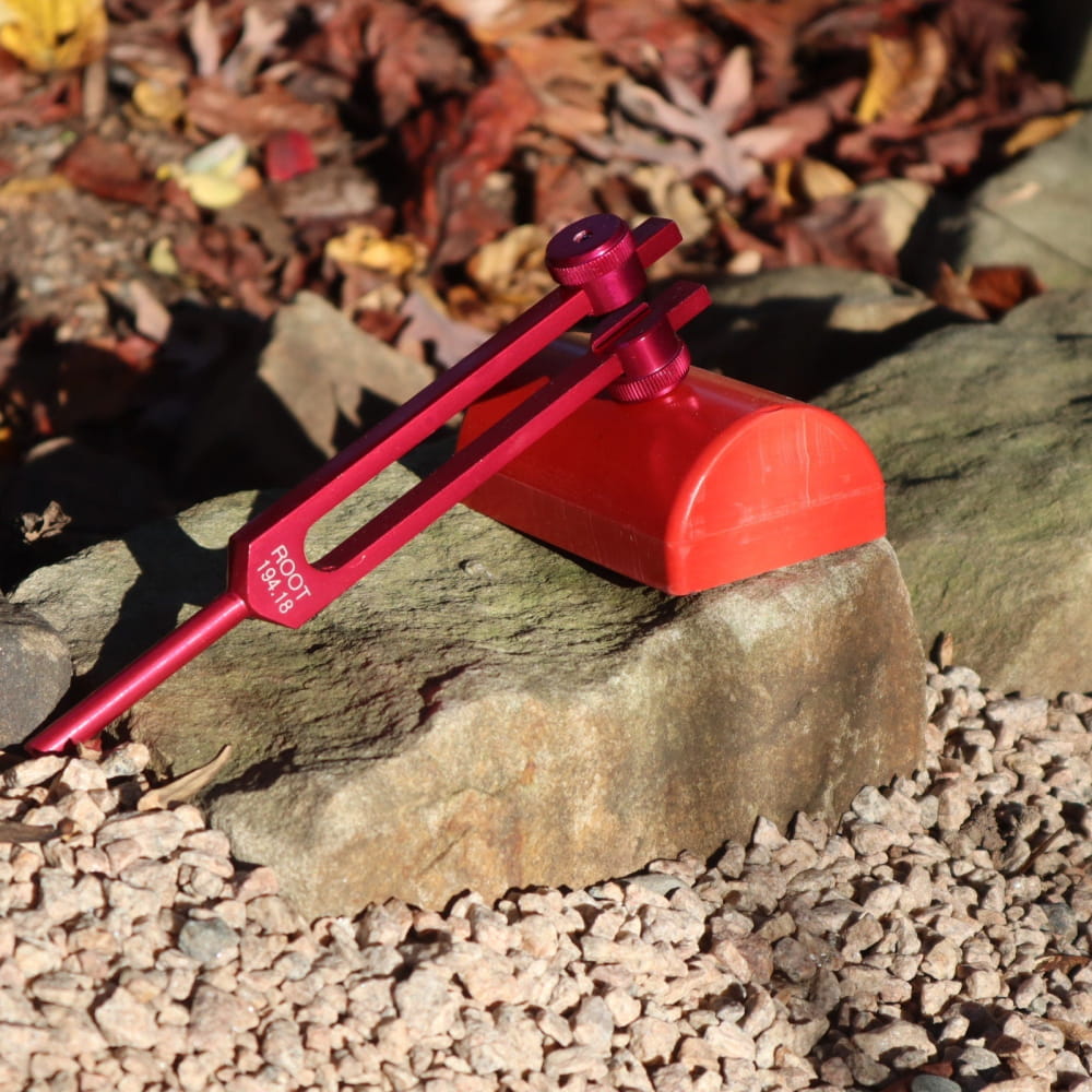 Red plastic slingshot on a rock near Healing Tuning Fork Activators product