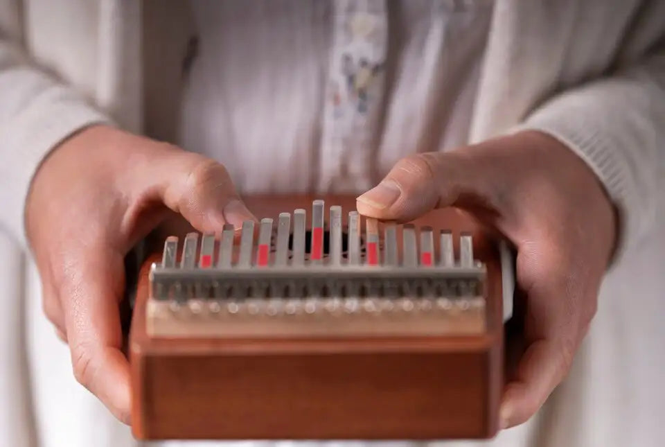 A wooden kalimba with silver-colored tines and red accents.