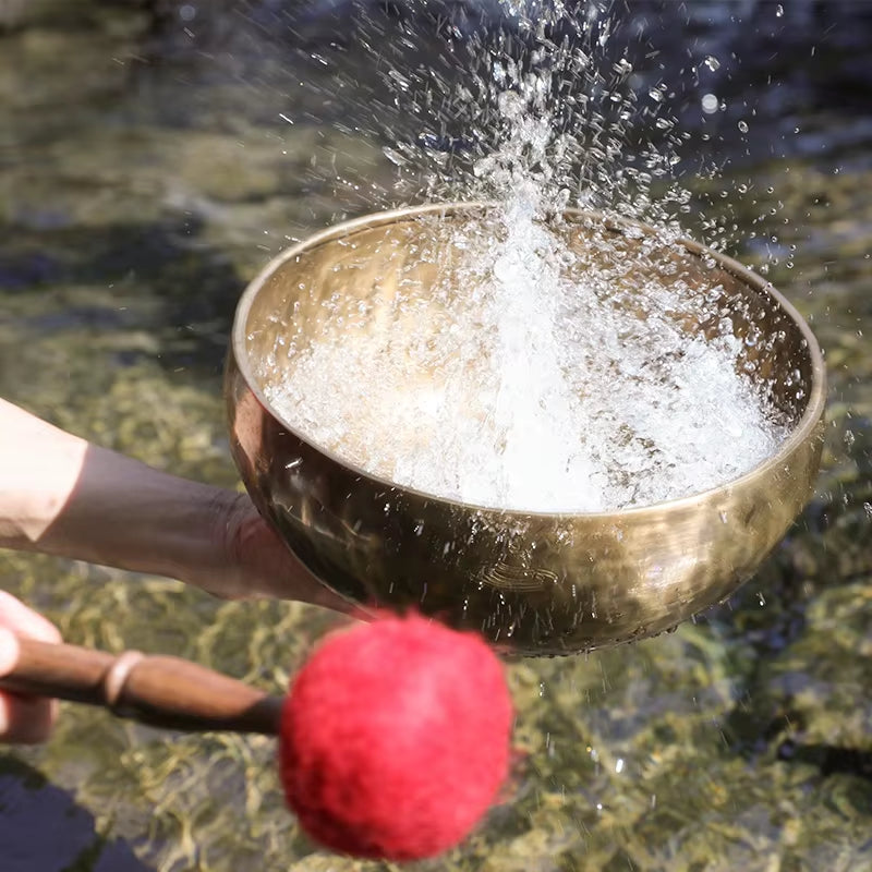 Tibetan singing bowl being struck with water splashing for meditation purpose