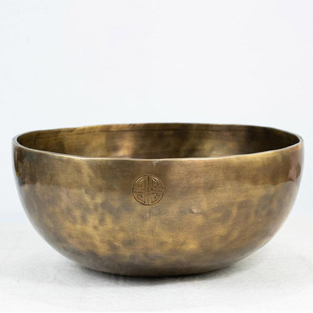 Hammered brass singing bowl with etched symbol design for healing and meditation