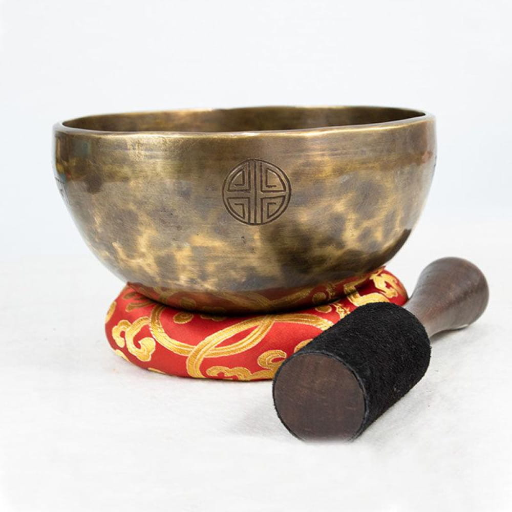 Bronze Tibetan Singing Bowl with Buddhist symbols on red cushion and wooden mallet