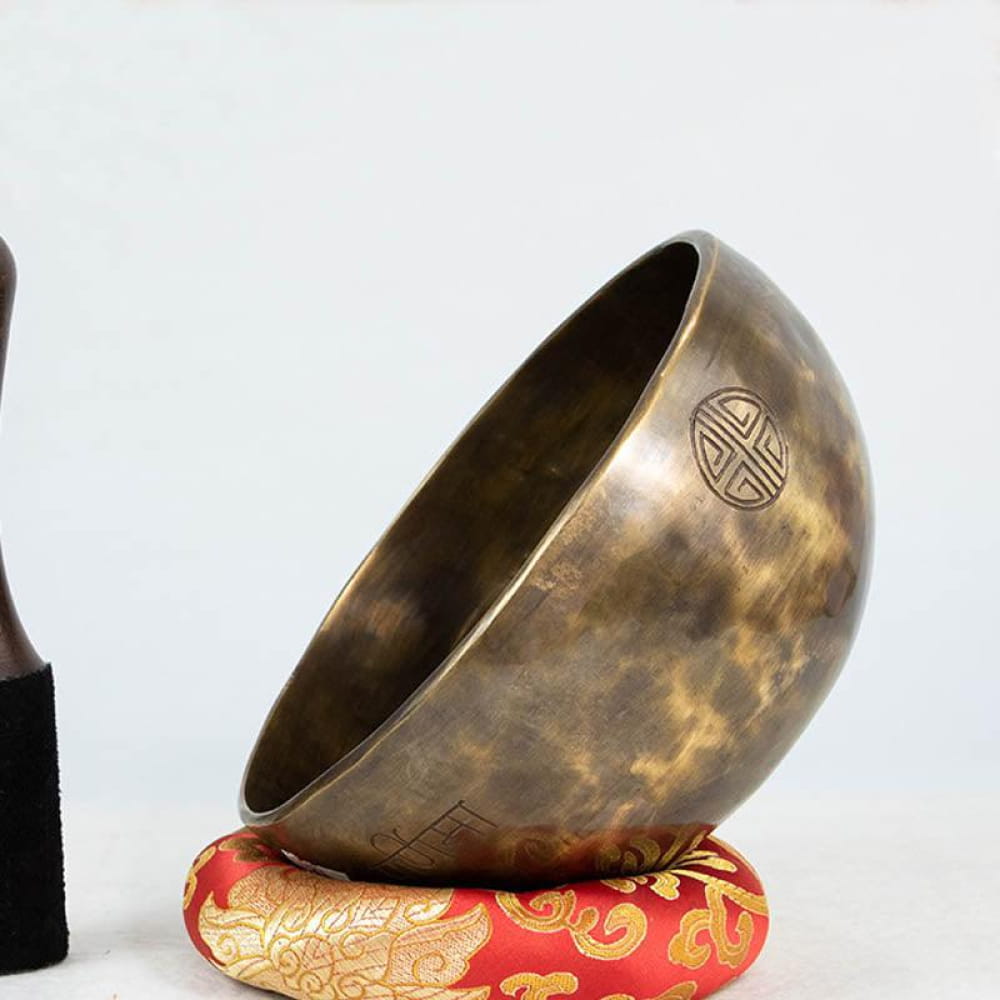 Bronze singing bowl on a red and gold cushion for healing in Buddhism