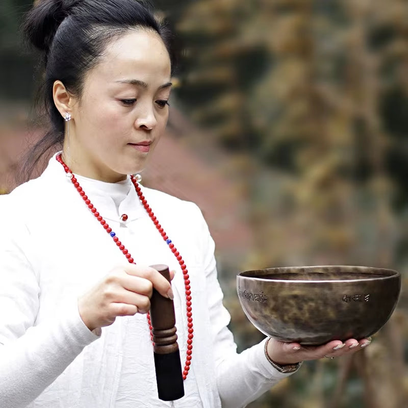 Dark Tibetan Singing Bowl with striker and red prayer beads for meditation therapy