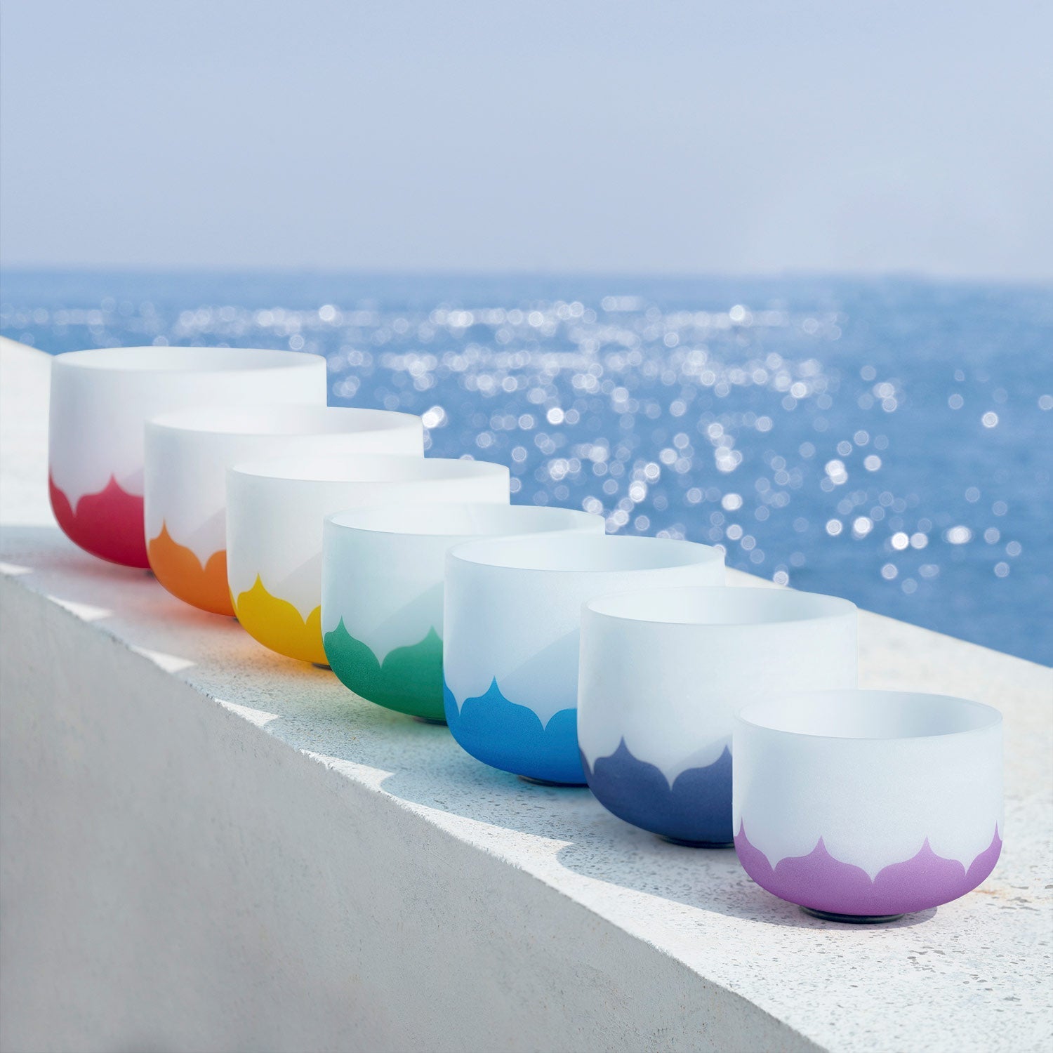 Row of white ceramic cups with rainbow bottoms in spectrum order for chakra healing