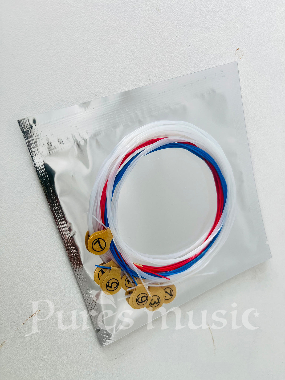 Red, white and blue Lyre Harp nylon strings with brass ball ends in clear package