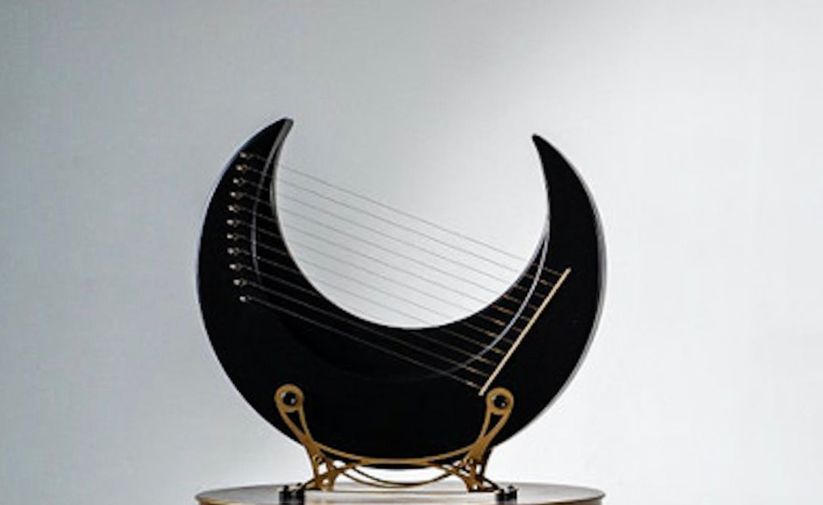 Crescent-shaped Black Moon Lyre Harp with delicate strings on a golden stand