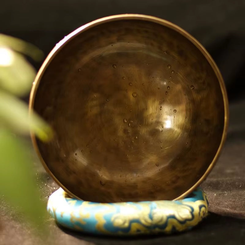 Tibetan singing bowl on a turquoise and gold cushion for a serene ambiance