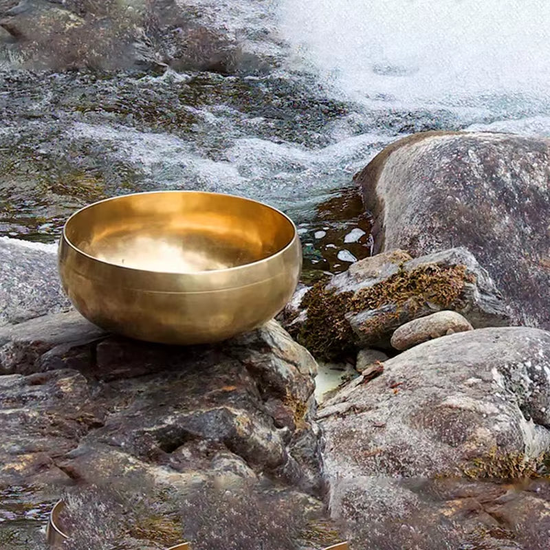 Golden Tibetan singing bowl on rocks for sound healing and meditation