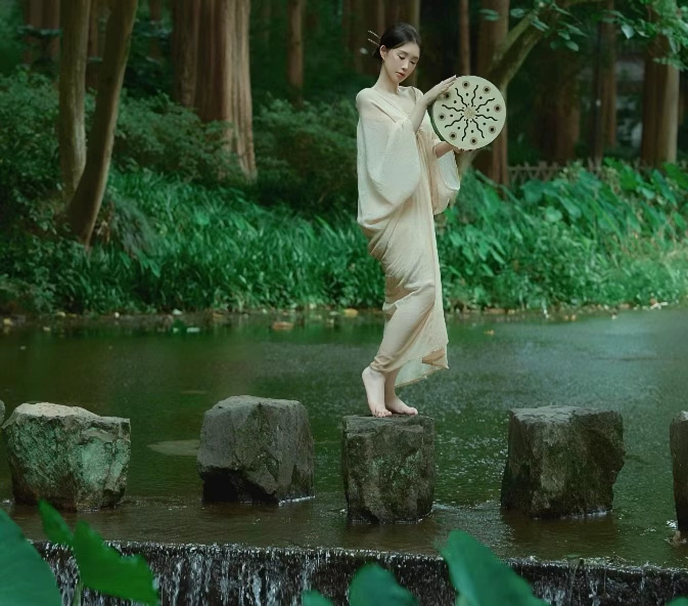 Woman in a flowing white dress crossing stepping stones with a circular fan, Ocean Drum