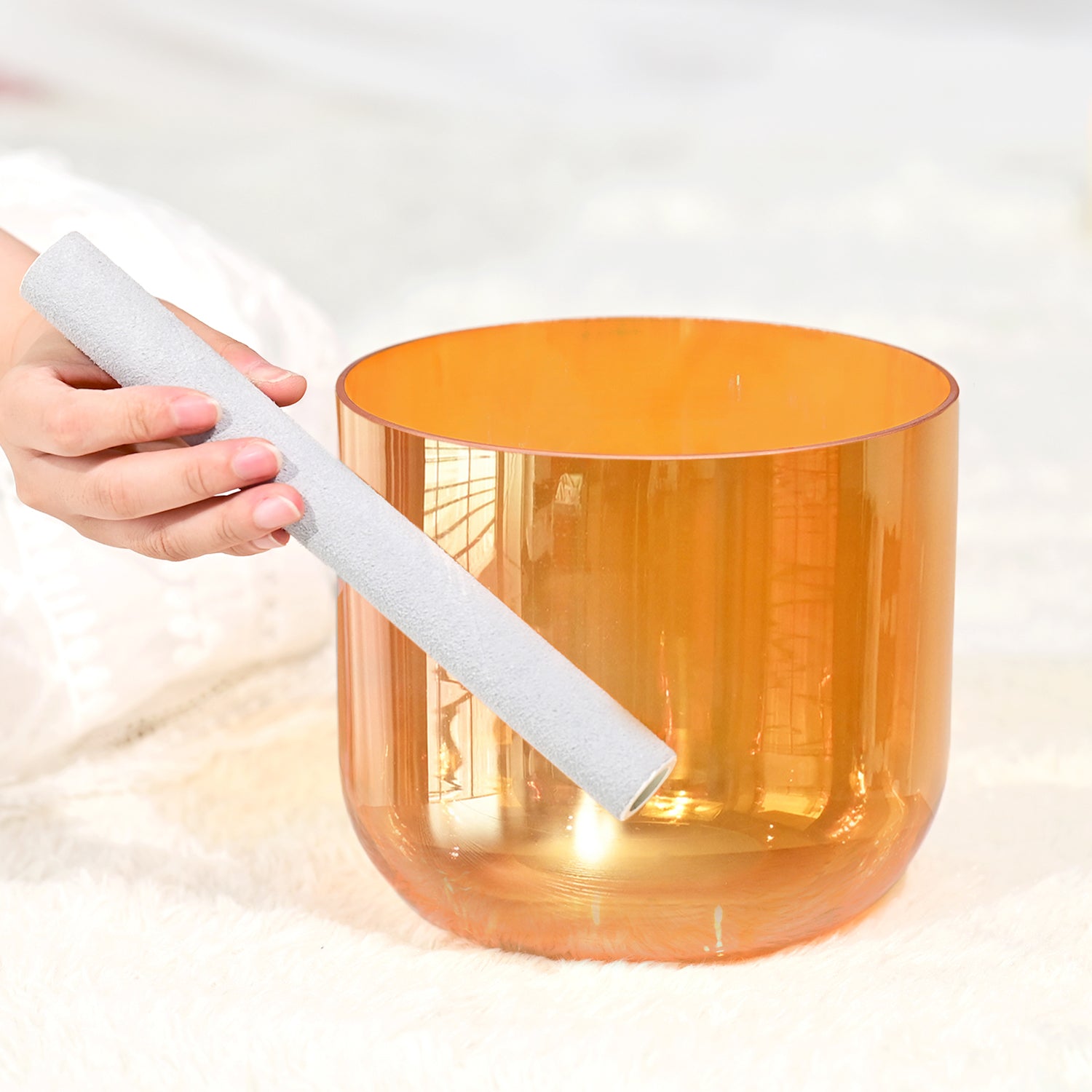 Orange translucent crystal singing bowl with white mallet for chakra meditation