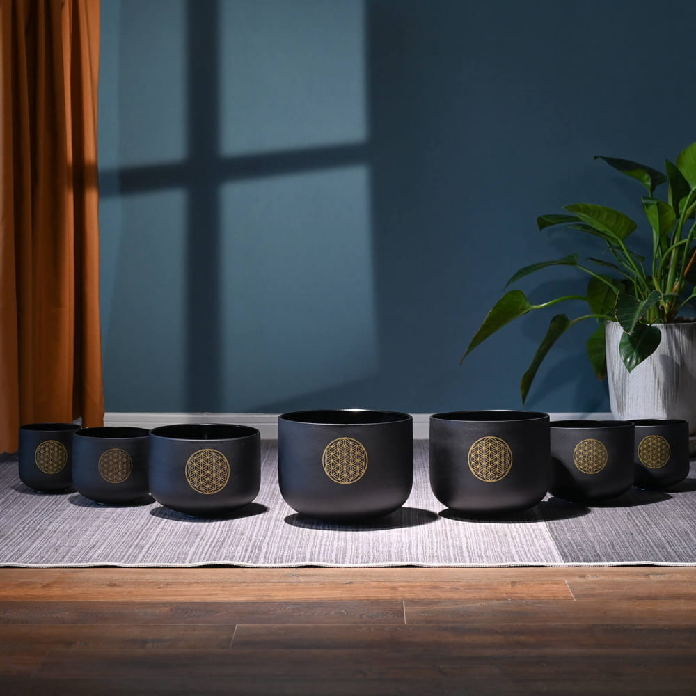 Row of black ceramic bowls with golden Flower of Life symbols in a singing bowl set