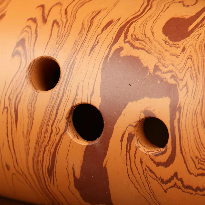 Three circular holes in a swirled copper-colored surface of a Professional 10-Hole Xun Flute