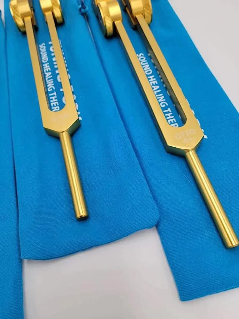 Gold-colored Otto Tuners Weighted Tuning Forks Set on blue fabric background