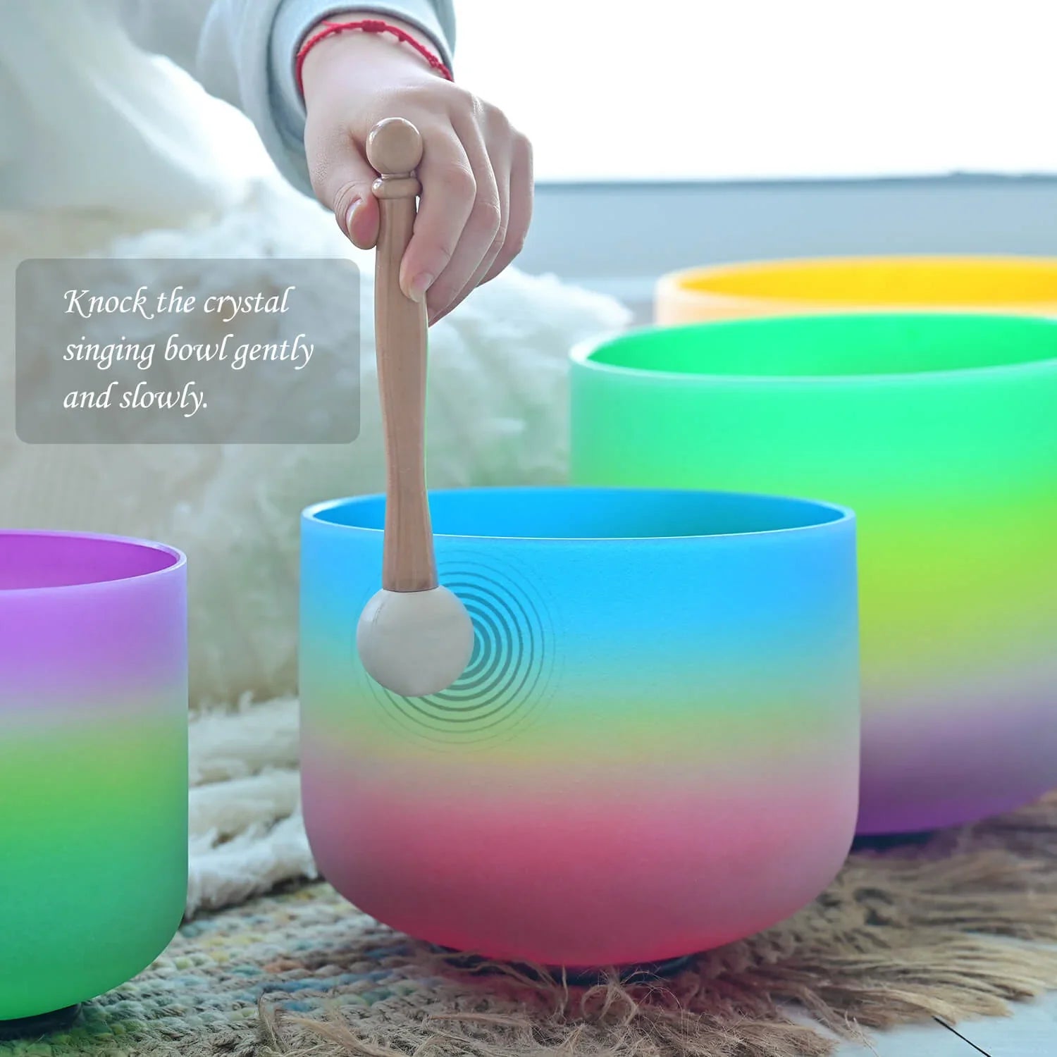 Rainbow-colored Crystal Singing Bowl being played with a mallet in a vibrant set