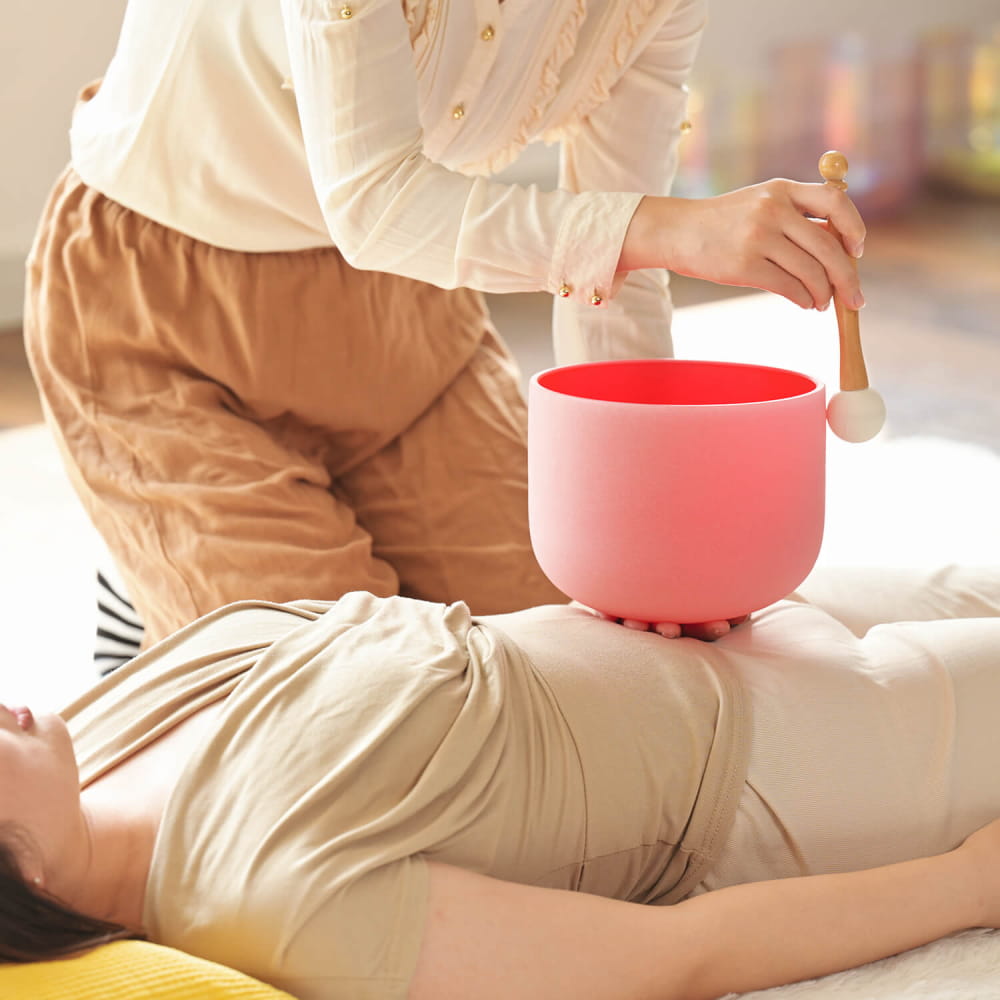 Pink Crystal Singing Bowl in use during a sound therapy session for Root Chakra healing