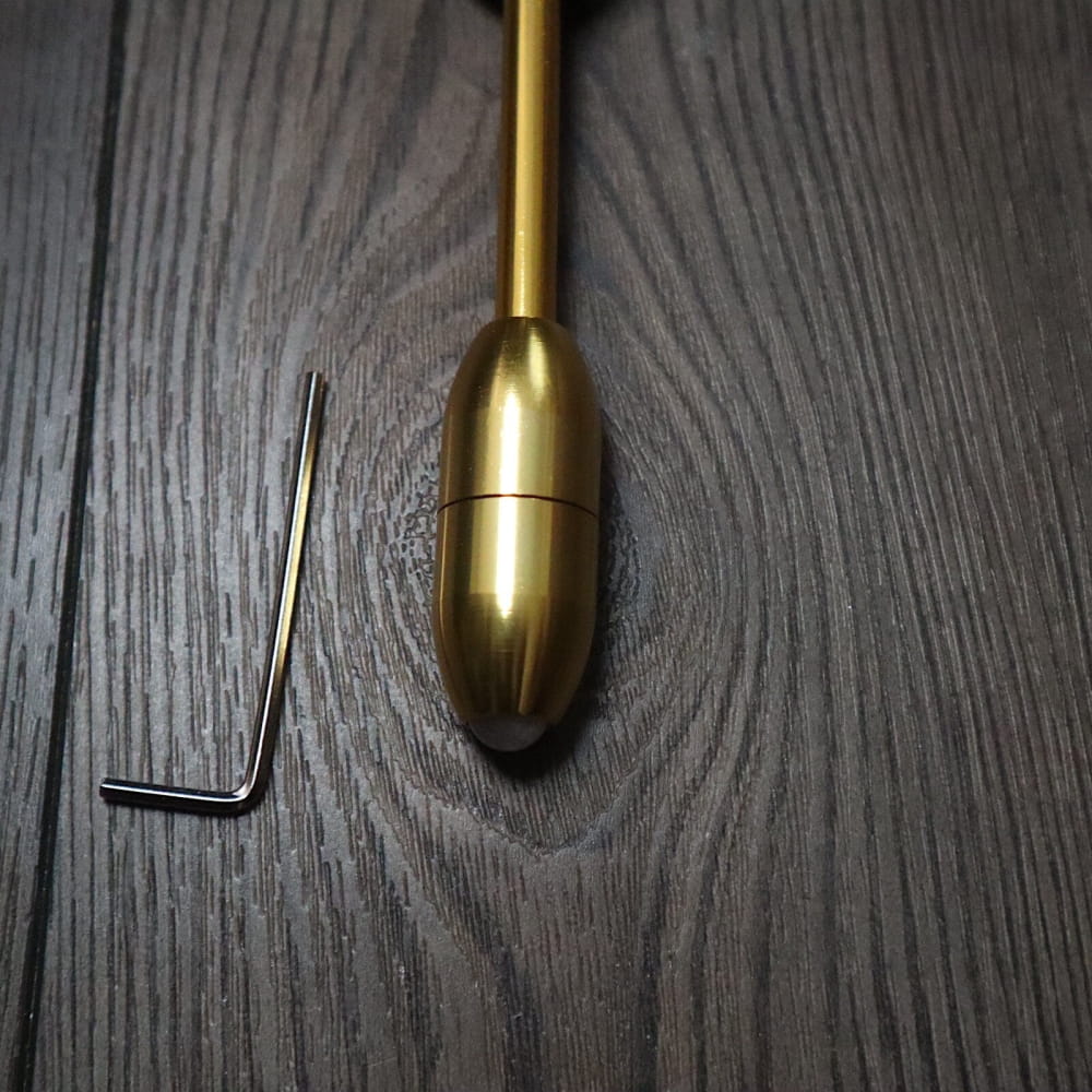 Brass bullet-shaped plumb bob with hex key beside Schumann 93.96Hz Tuning Fork