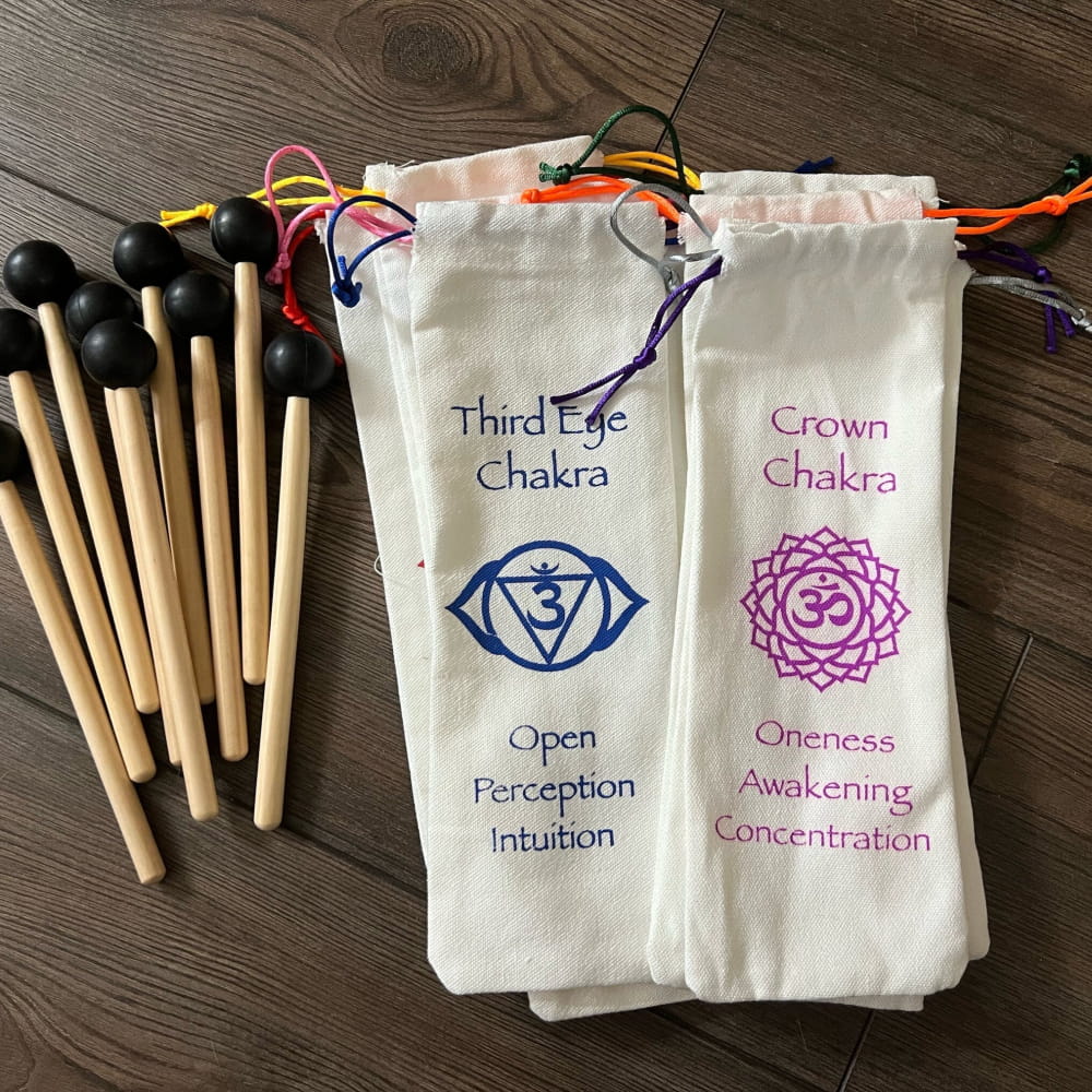 Chakra-themed cloth bags and wooden mallets next to Silver Chakra Tuning Forks Set