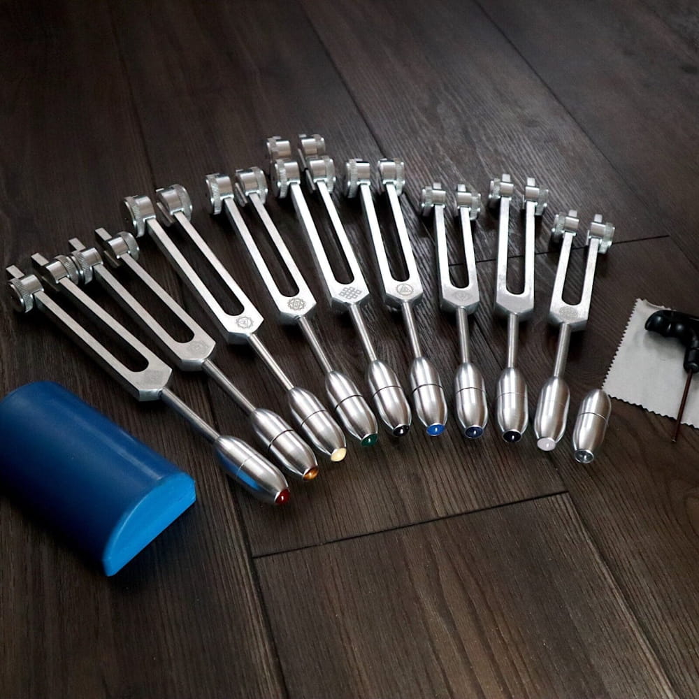 Collection of Silver Chakra Tuning Forks arranged in a fan pattern for crystal massage