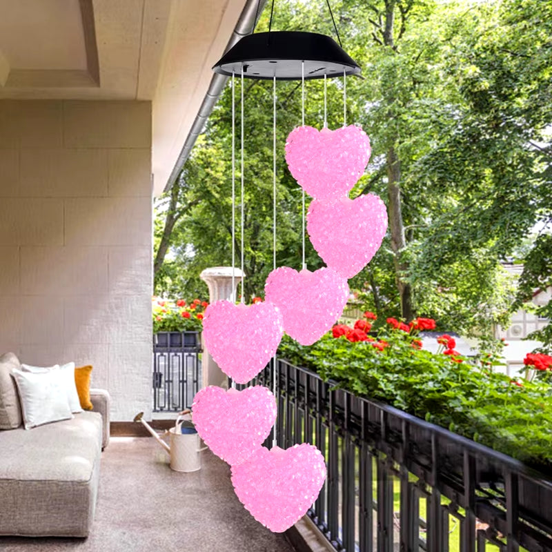 Pink heart-shaped wind chimes hanging from a black umbrella top for garden decor